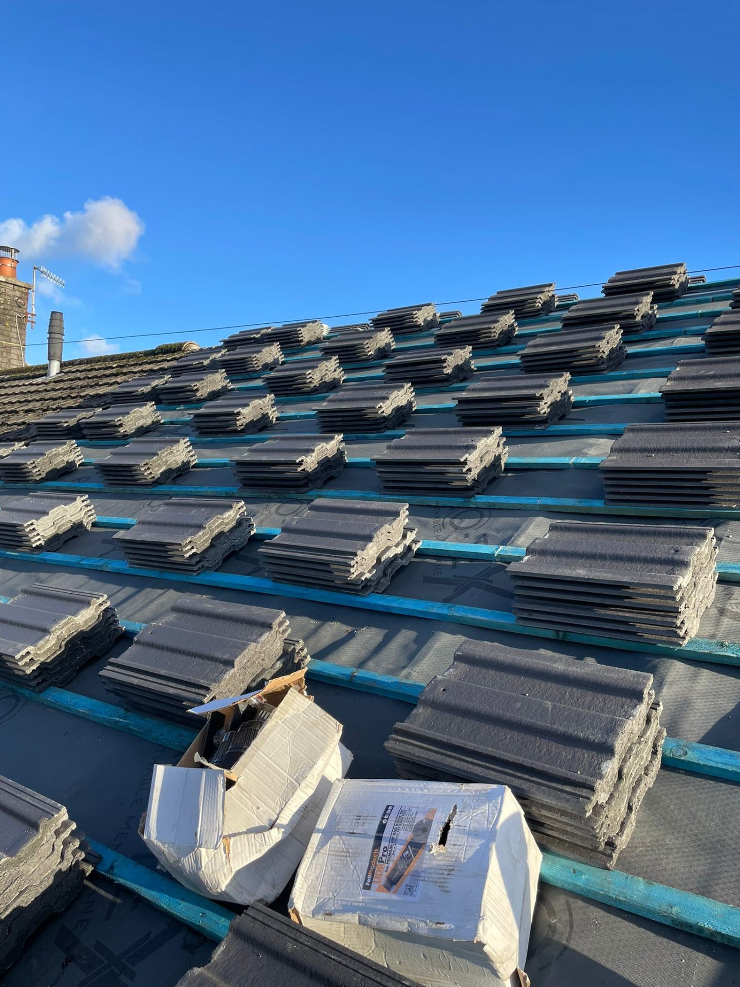 Concrete roof tiles stacked on battens during a full roof replacement